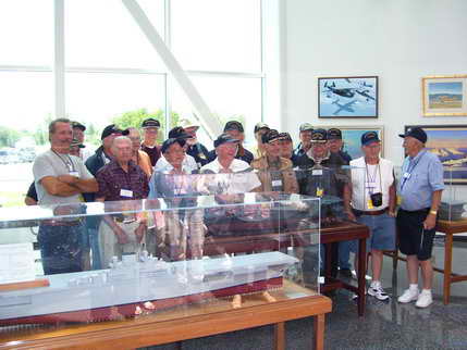 Crew of the Kalinin Bay at their ship's model at the Air Museum